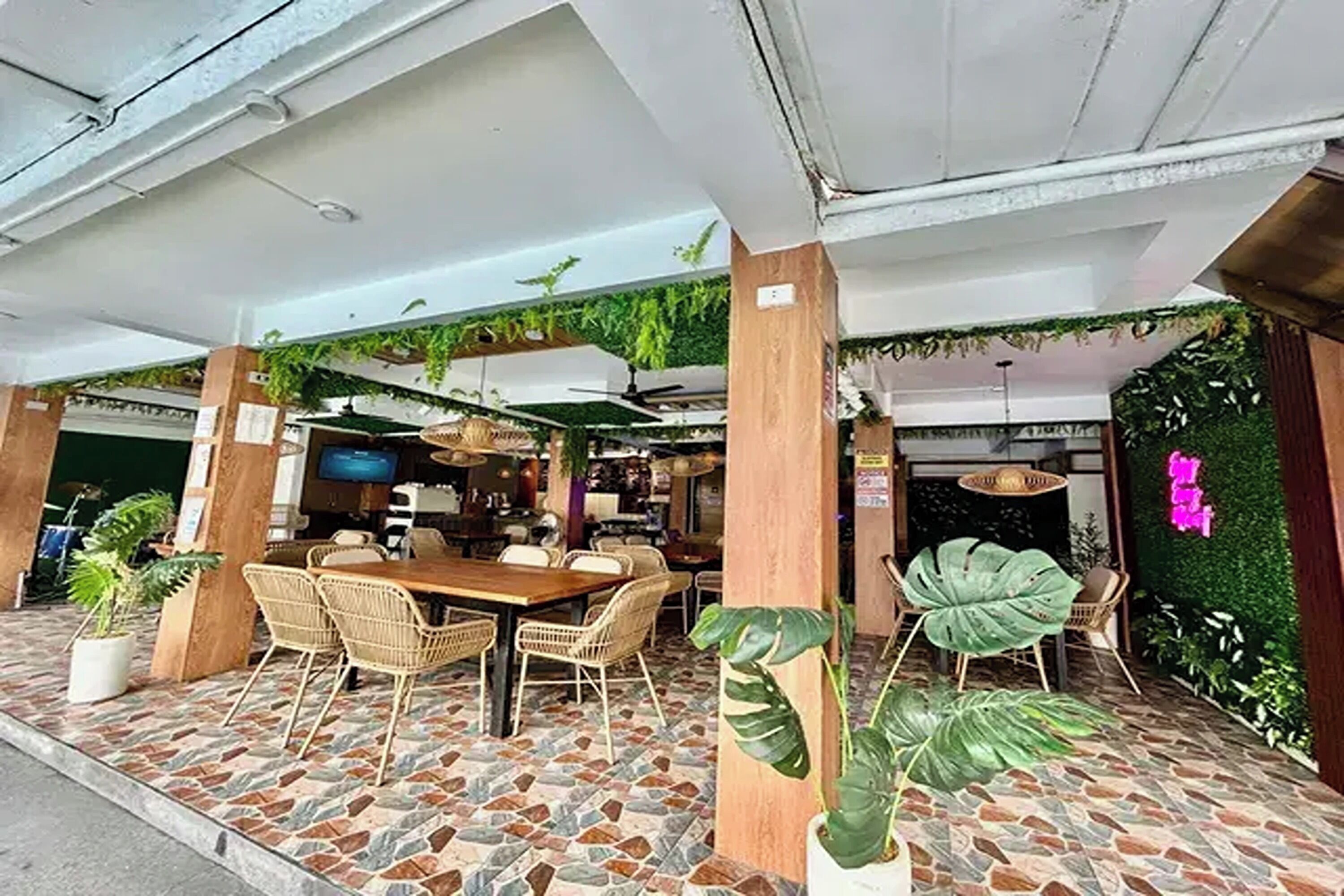 An outdoor dining area with a stone-tiled floor, wicker furniture, and green plants.