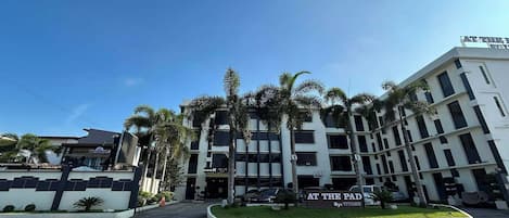 Un hotel de varios pisos con un letrero que dice 'AT THE PAD' y 'By: TITANS'.