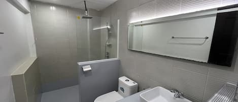 Un baño moderno con ducha, inodoro y dos lavamanos.