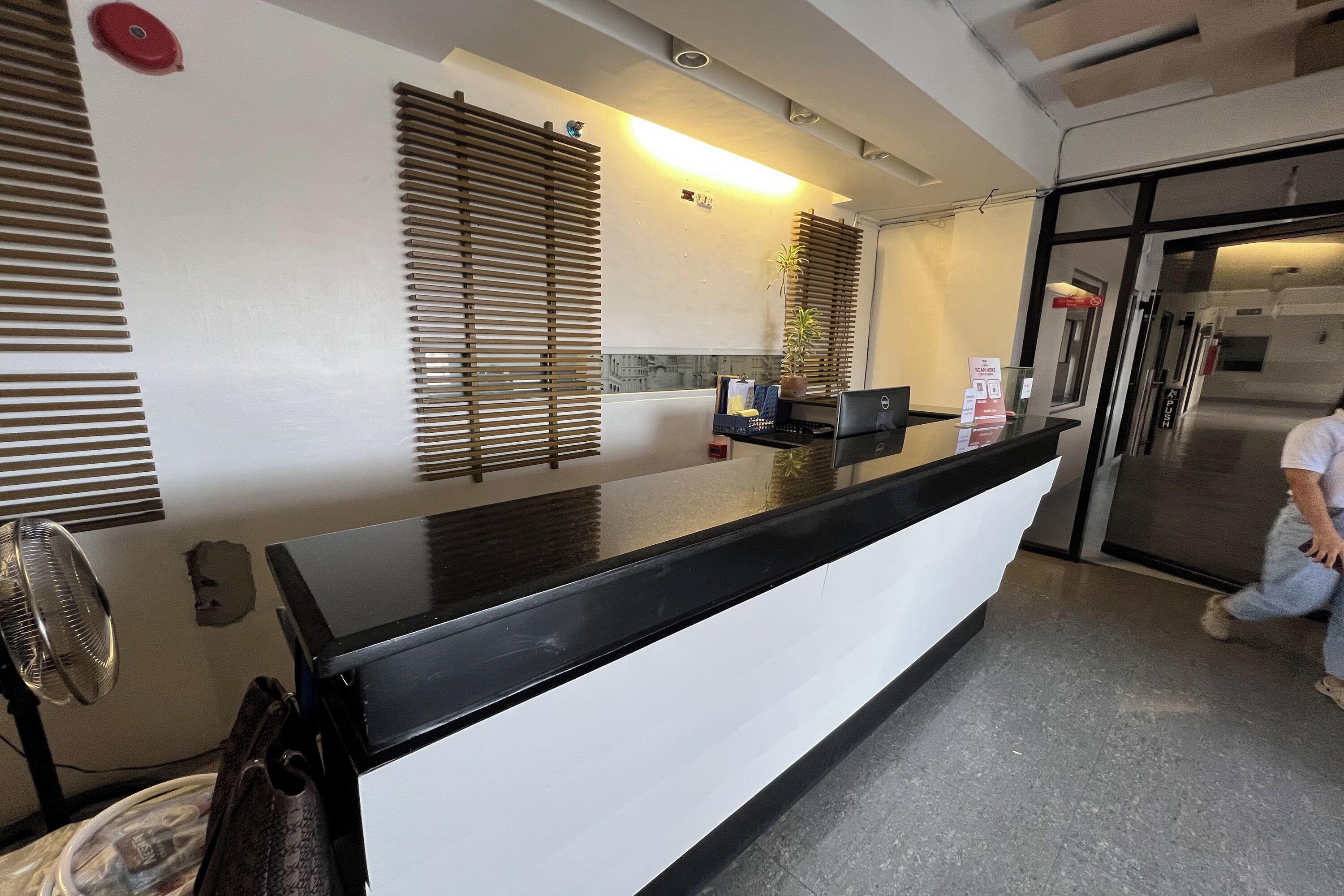 A hotel reception area with a black counter, a fan, and a refrigerator.