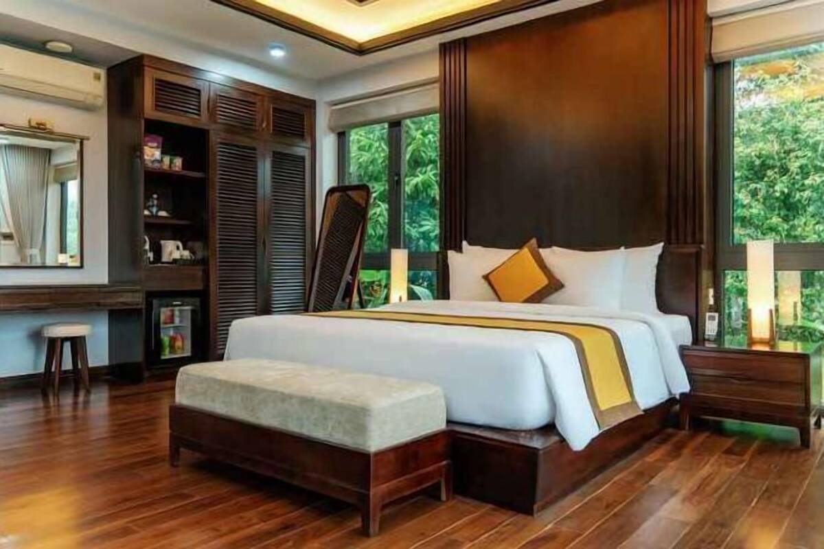 A bedroom with a large bed, a wooden bench, a wardrobe, a mirror, and a nightstand.