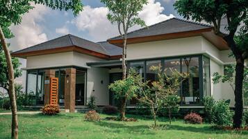 Ein modernes, zweistöckiges Haus mit großer Glasfassade, einer Holztreppe und einem gepflegten Garten.