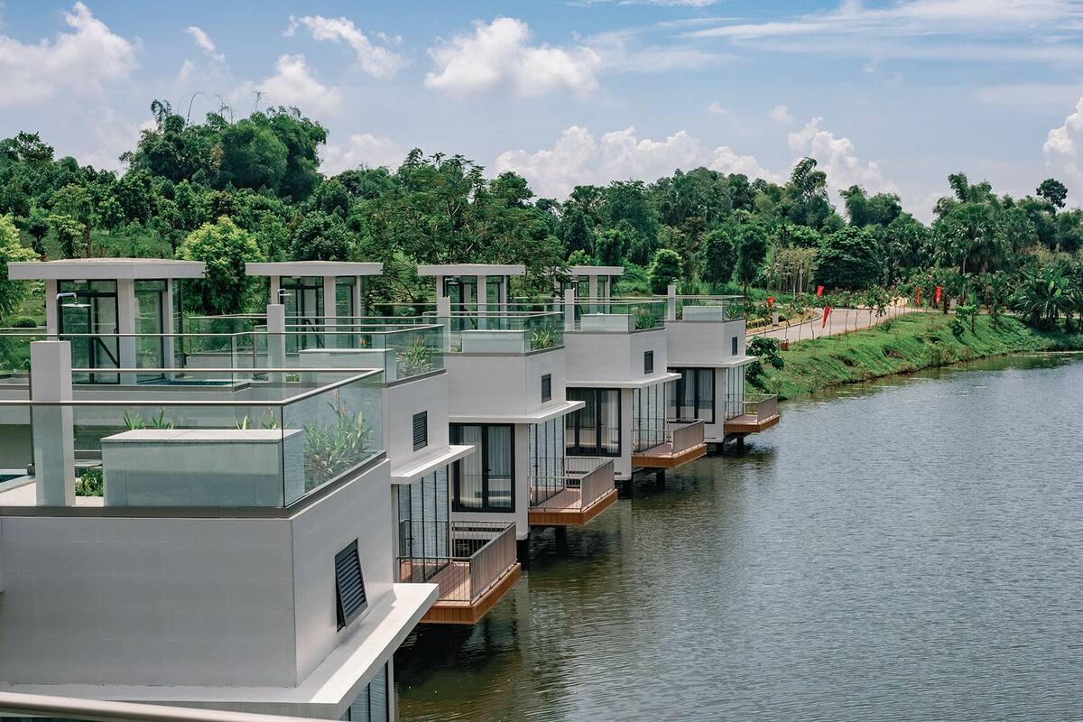 Floating villas with glass balconies, wooden decks, and a river view.