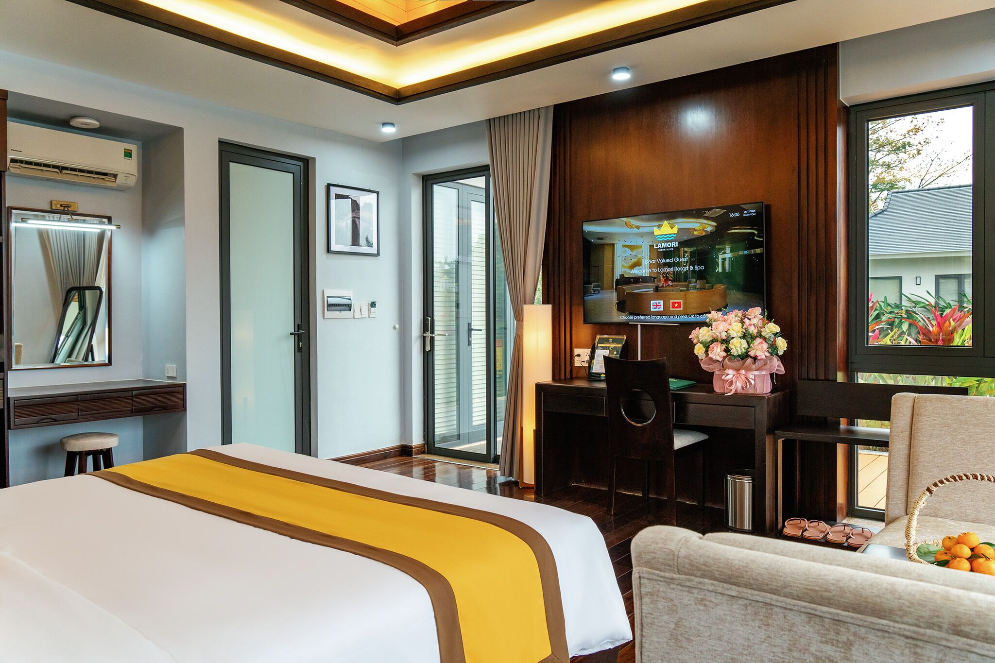 A hotel room with a bed, a desk, a TV, and a view of the outdoors.