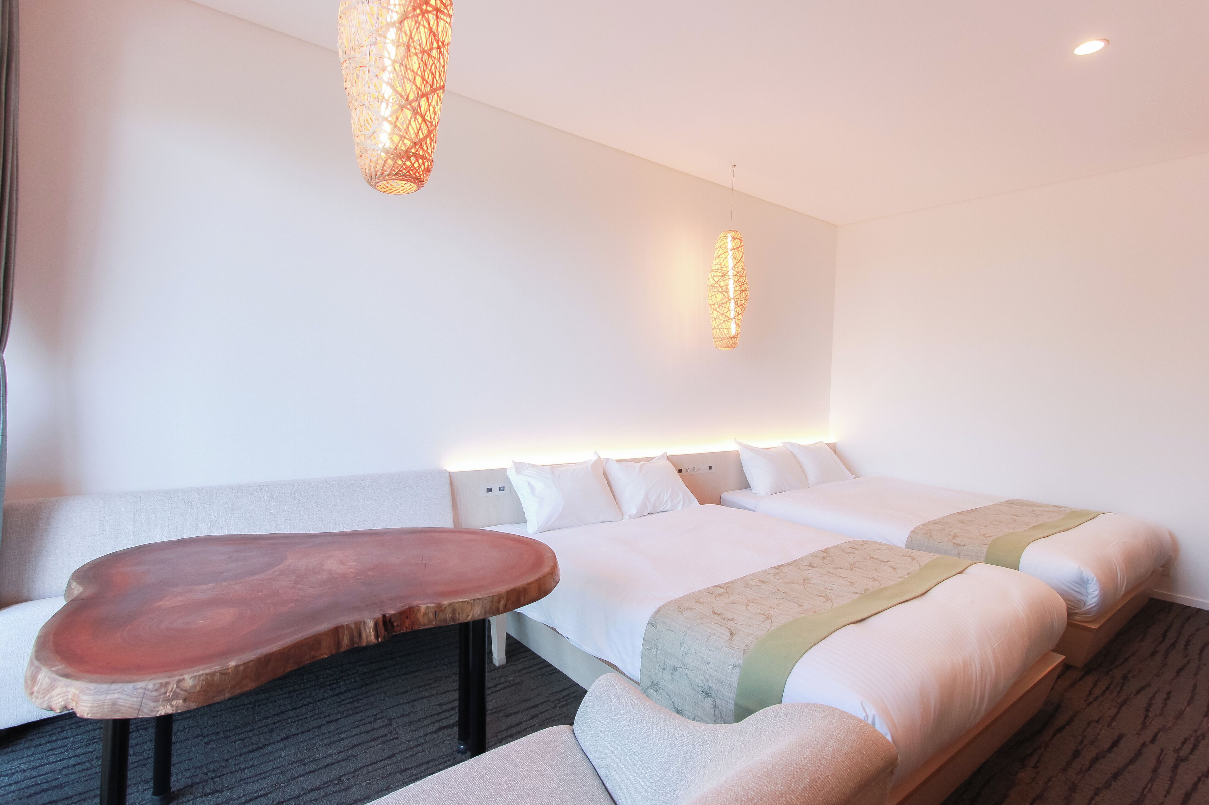 Una habitación de hotel con una cama grande, una mesita de madera y una lámpara colgante.