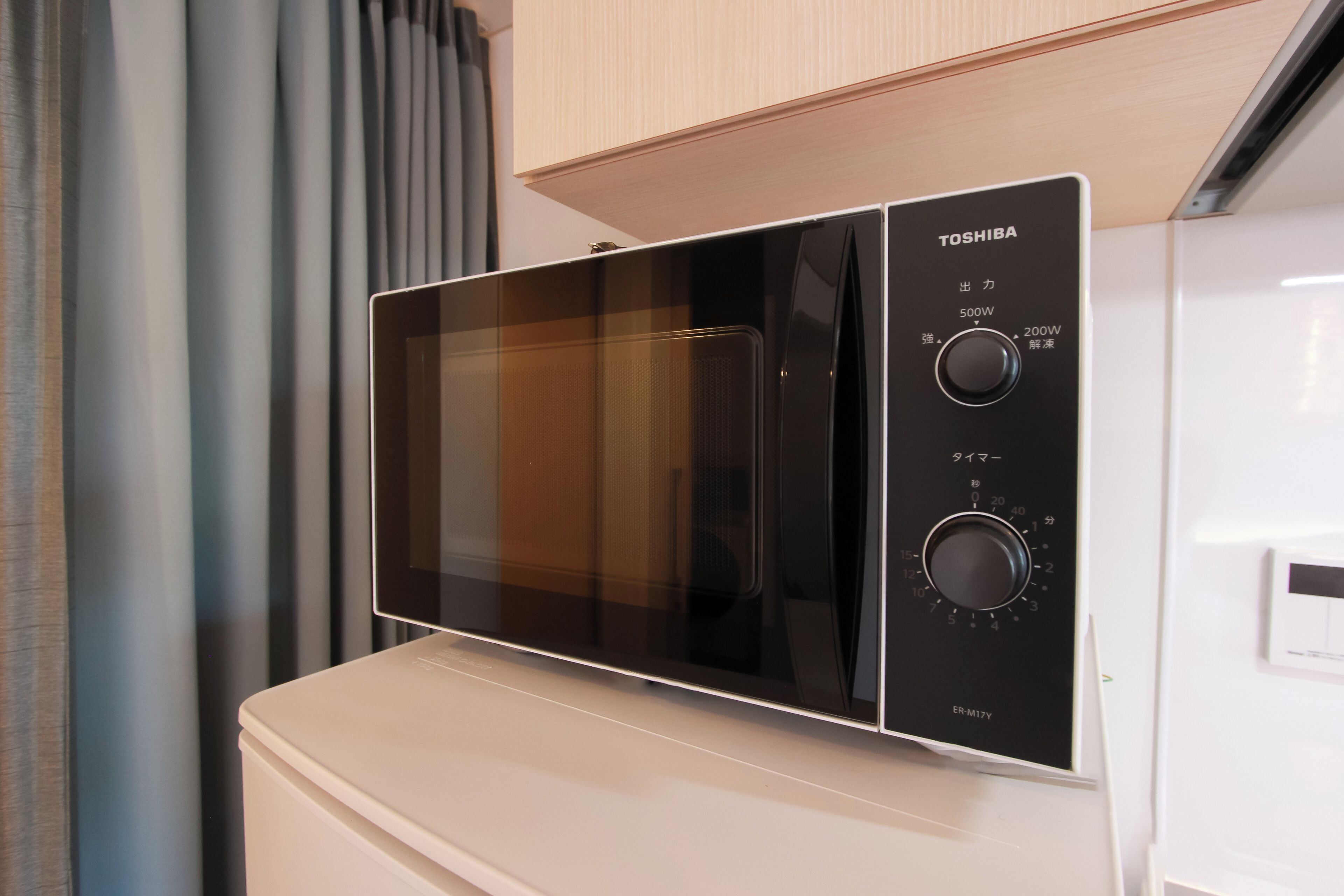 A Toshiba microwave oven with a digital control panel, placed on a white countertop.