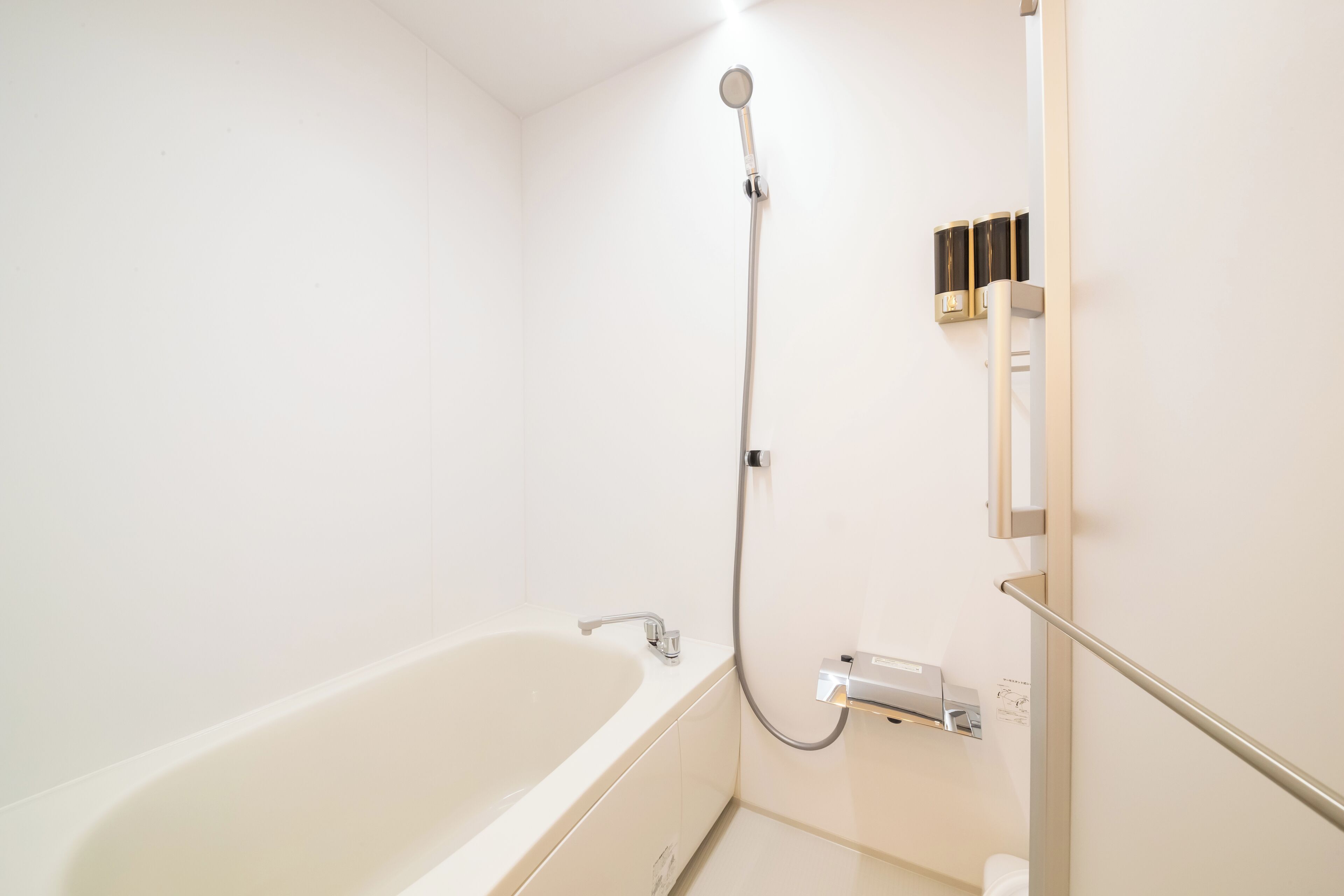 Une salle de bain avec une baignoire blanche, une pomme de douche et un porte-serviettes.