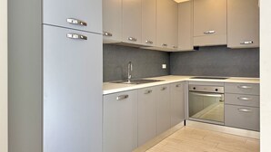 Una cocina moderna con armarios grises, un horno de acero inoxidable y un lavavajillas integrado.