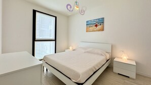 Un dormitorio moderno con una cama, mesitas de noche, un ventanal con persianas, un cuadro en la pared y una lámpara colgante.
