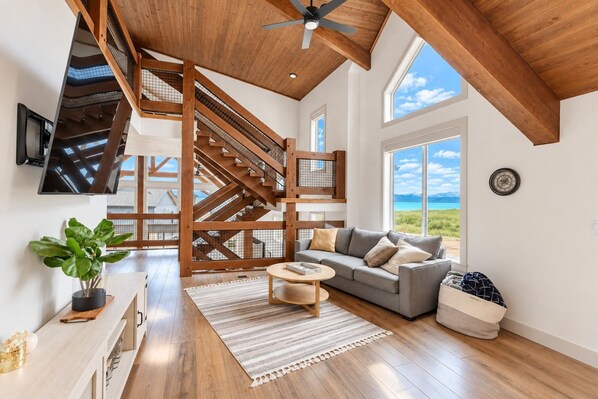 A spacious living area with a wooden staircase, a sofa, and a view of the outdoors.