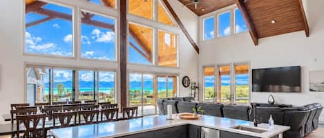 A spacious kitchen with a large island, dark cabinetry, and a view of the ocean.