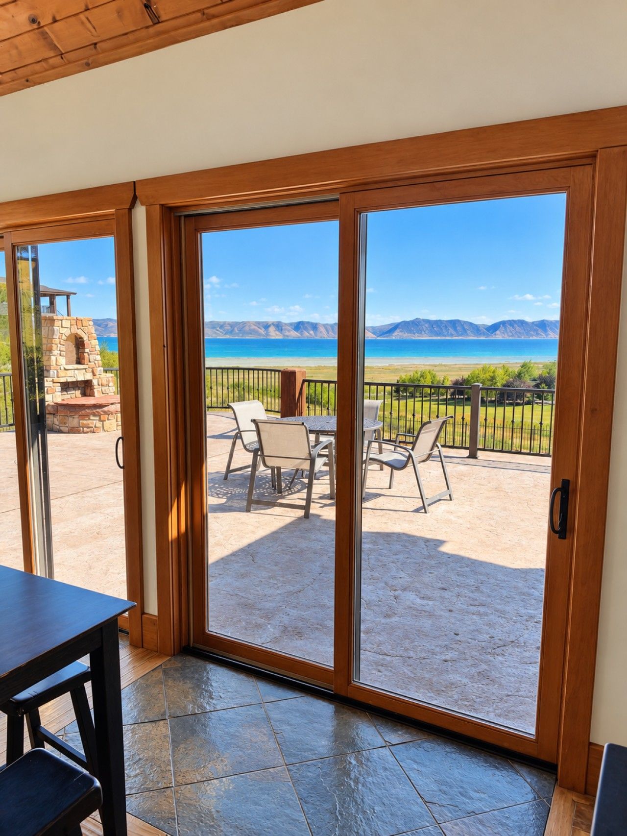 Une pièce dotée d’une porte-fenêtre coulissante donnant sur un patio extérieur avec une cheminée en pierre, une table et des chaises.