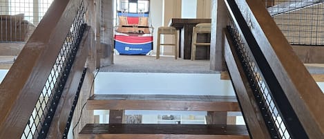 A wooden staircase with metal railings leading to a seating area with a view of a basketball hoop.