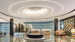 En modern entréhall med en rundformad lampa, sittgrupper och en receptionsdisk.
