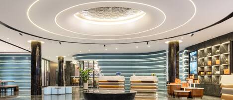 Een moderne lobby met een ronde lamp, zithoeken en een receptiebalie.