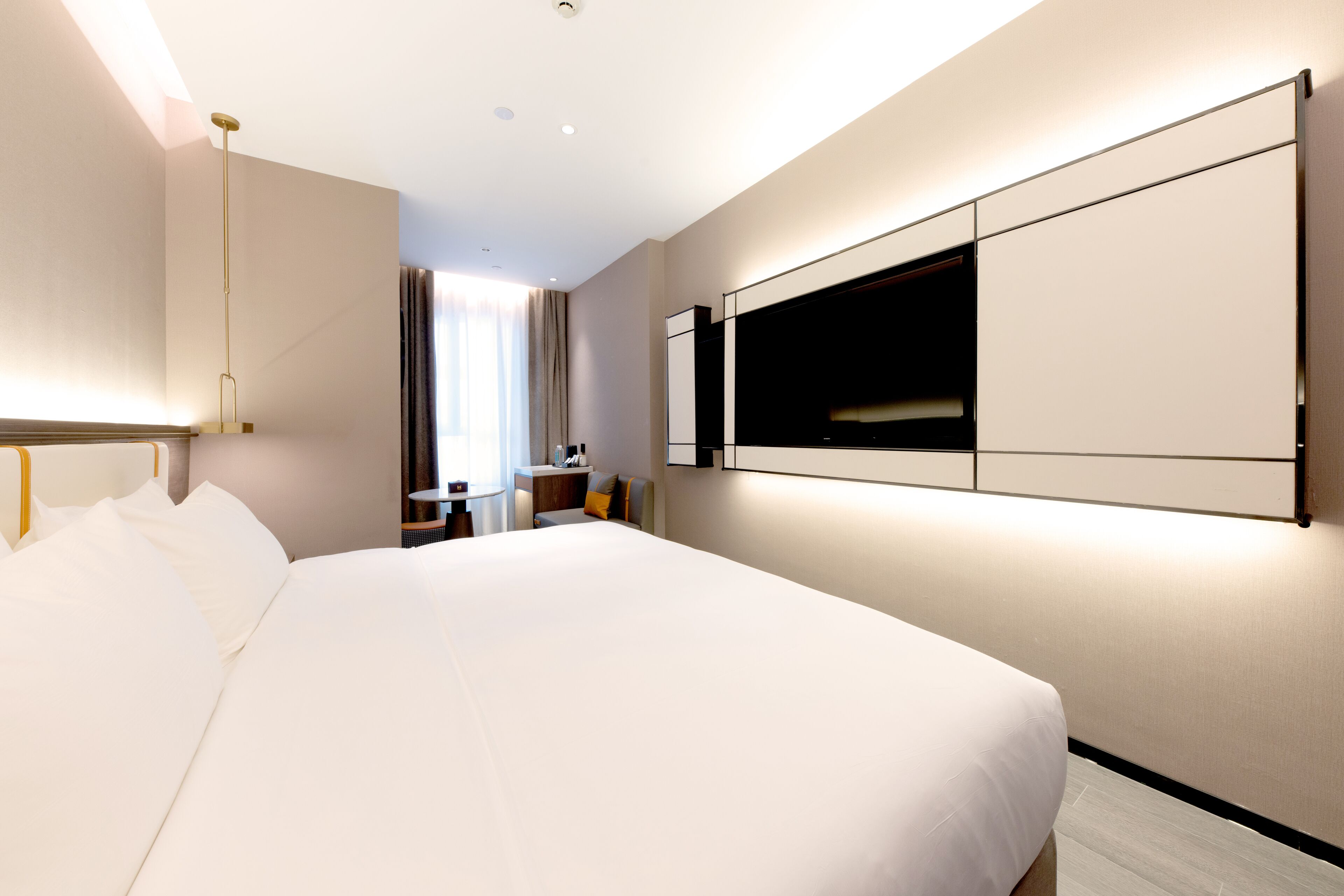 Una habitación de hotel moderna con una cama grande, un televisor de pantalla plana montado en la pared y un escritorio con una silla.
