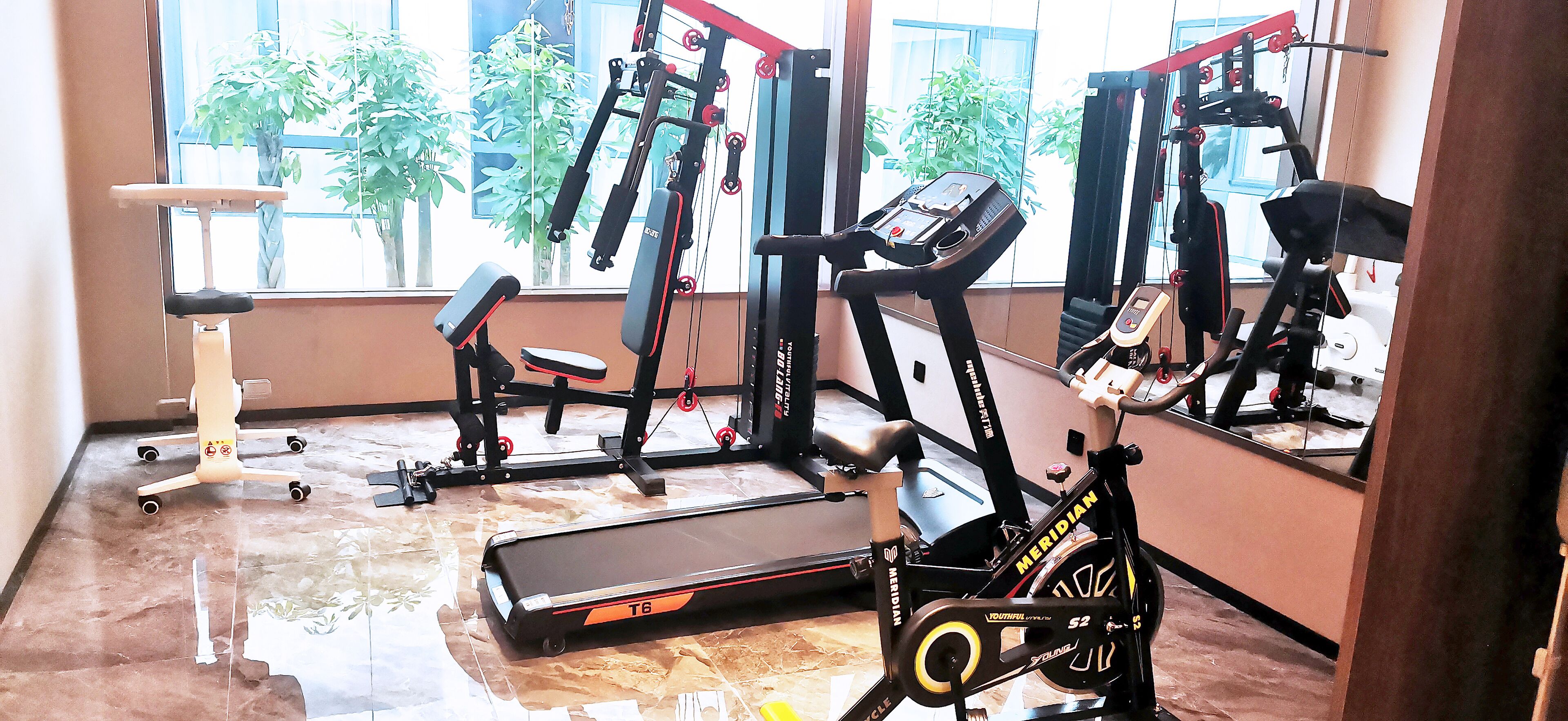 A gym with exercise equipment including a treadmill, stationary bike, and weight machines.