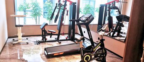 A gym with exercise equipment including a treadmill, stationary bike, and weight machines.