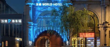 La entrada del Hotel Tianhe World, con señalización iluminada y una estructura en arco distintiva.
