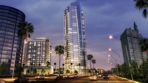 A modern high-rise building with multiple floors, surrounded by palm trees and other urban structures.