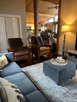 Ein Wohnzimmer mit einem blauen Sofa, einem braunen Ledersessel, einem grauen Hocker und einem Teppich mit Muster.