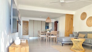 Una sala de estar moderna con un sofá gris, una mesa de centro de madera y un comedor con sillas y una mesa de madera.