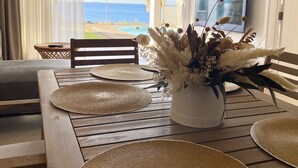 Un comedor con vista al océano, un ventilador de techo y un televisor en la pared.