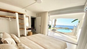 Un dormitorio con una cama grande, un vestidor y vistas a una piscina y al océano.
