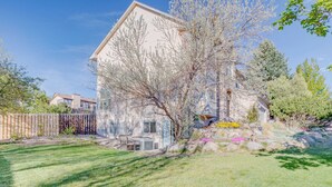 A house with a sloped roof, a fenced yard, and a tree in front. - Charming 1-bdrm walkout basement suite with AC, WiFi in lovely Colorado Springs (Colorado Springs)