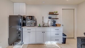 A compact kitchen with white cabinets, a stainless steel refrigerator, a microwave, a toaster, and a sink. - Charming 1-bdrm walkout basement suite with AC, WiFi in lovely Colorado Springs (Colorado Springs)