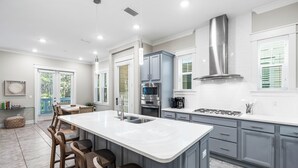 Una cocina moderna con una isla grande, electrodomésticos de acero inoxidable y muebles grises.