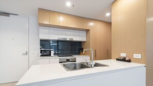 Une cuisine moderne avec des meubles blancs, un évier en acier inoxydable et un four à micro-ondes.