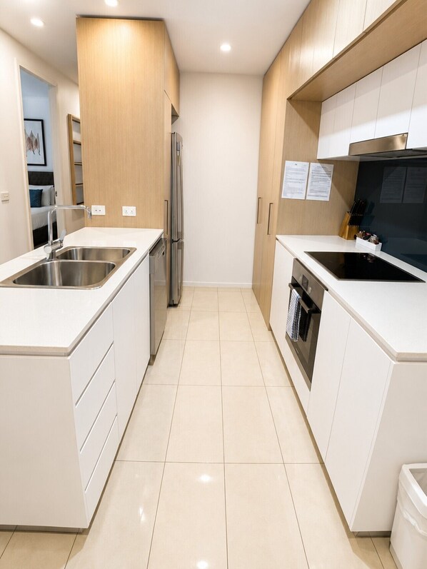 Cocina moderna con armarios blancos, electrodomésticos de acero inoxidable y piso de baldosas.