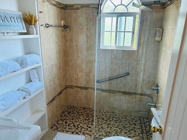 A shower with a glass door, a handrail, and a tiled floor. - 3 BEDROOMS - 3 BATHROOMS OCEAN VIEW PENTHOUSE (Ocho Rios)