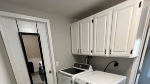 A compact laundry room with a washing machine, dryer, and a small sink.