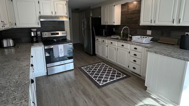 A modern kitchen with white cabinets, stainless steel appliances, and a granite countertop.