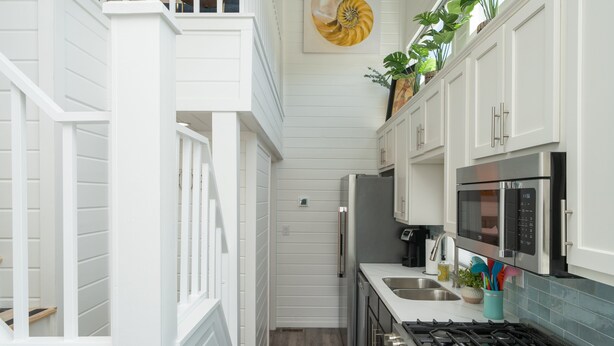 A narrow kitchen with white cabinetry, a stainless steel refrigerator, a microwave, and a gas stove. - Blue Bliss, Private Hot Tub & Fenced Yard at Roadrunner Resort (Parker)