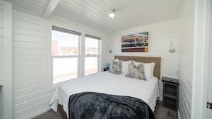 A bedroom with a large bed, a wooden headboard, a nightstand, and a painting above the bed.