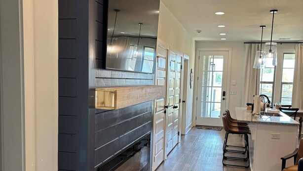 A modern kitchen with a built-in oven, a large mirror, and a dining area with a bar. - Charming & Spacious Townhome on North College Street in Auburn (Auburn)
