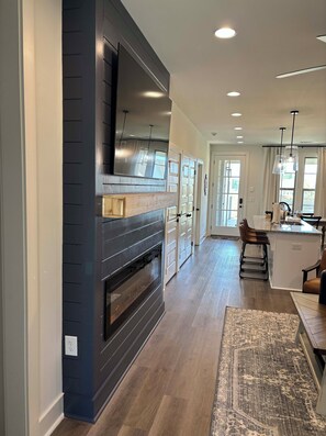 A modern kitchen with a built-in oven, a large mirror, and a dining area with a bar. - Charming & Spacious Townhome on North College Street in Auburn (Auburn)