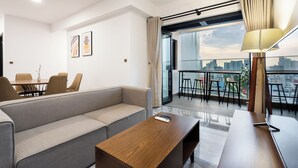 A modern living room with a sofa, a wooden coffee table, and a dining area with chairs and a table. - Luxury D1 Mension Condotel (Ho Chi Minh City)
