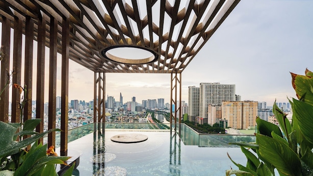 A rooftop infinity pool with a city view, surrounded by greenery and a wooden pergola structure. - Luxury D1 Mension Condotel (Ho Chi Minh City)