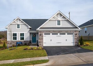 A two-story house with a stone facade, a front garage, and a well-maintained lawn.