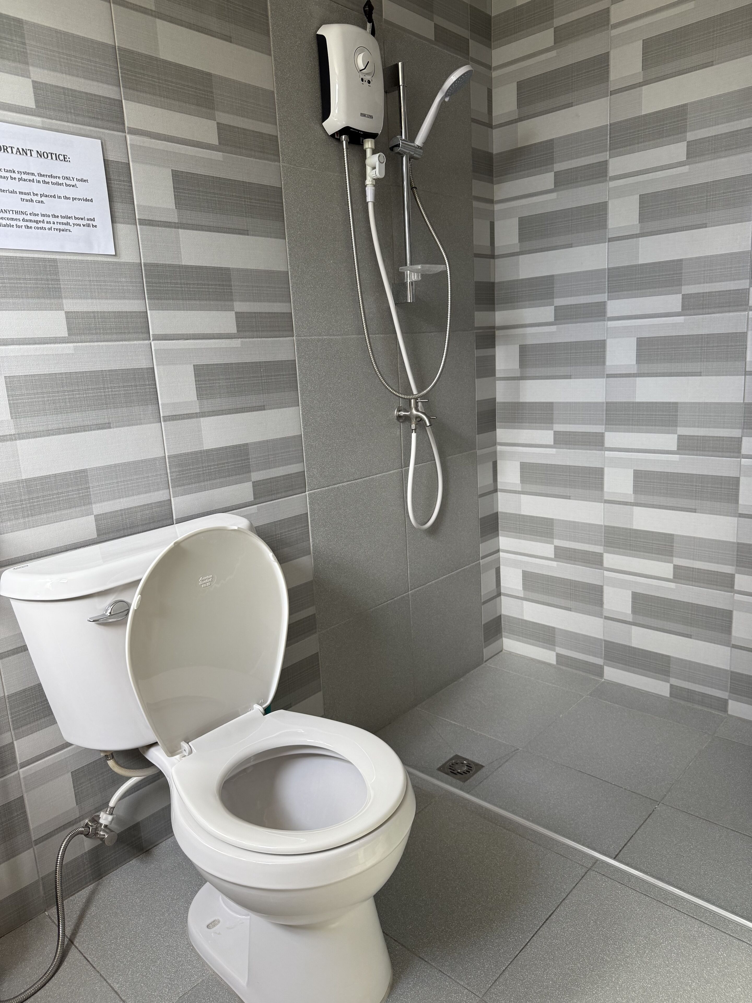 A modern bathroom with a toilet, a shower, and a hand dryer.