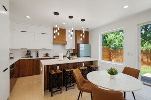 Een moderne keuken met houten kastjes, een centraal eiland, barstoelen en hanglampen.