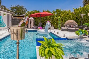 A pool area with a champagne bucket, lounge chairs, and a decorative unicorn float. - Spacious Luxury Oasis + Heated Pool+Jacuzzi+8P Tiki Bar- Beach Vibes Awaits You! (Boynton Beach)