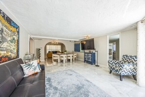 Relax in a stylish living area with a black leather sofa, flat-screen TV, and colorful artwork.