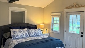 A bedroom with a bed, a ceiling fan, an air conditioning unit, a window, and a door.