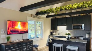 Una cucina moderna con TV, mobili scuri, un forno a microonde e una finestra vista.