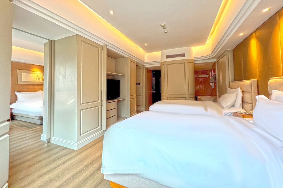 Una habitación de hotel con dos camas, televisor y armario.